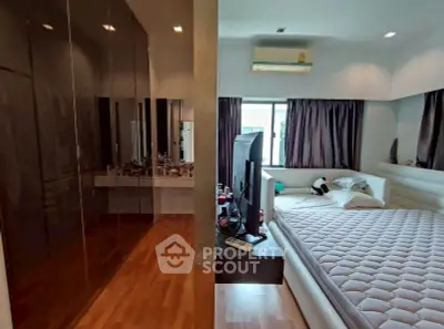 Spacious bedroom with modern decor and large windows for natural light.