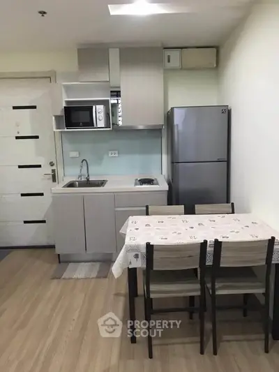 Modern compact kitchen with dining area in a cozy apartment, featuring sleek appliances and contemporary design.