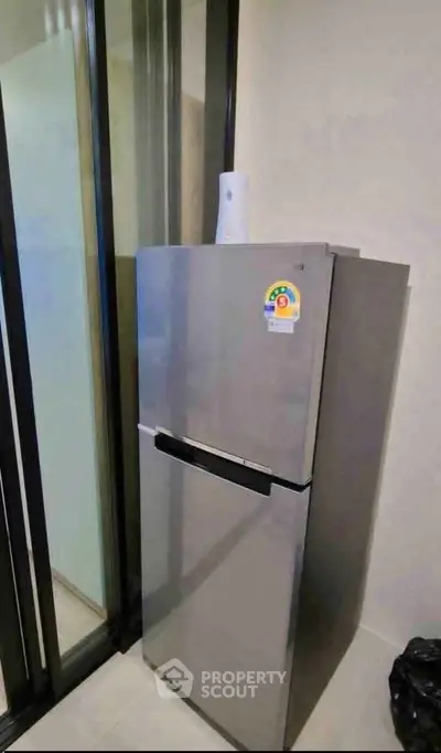 Modern kitchen with sleek stainless steel refrigerator and glass sliding doors.