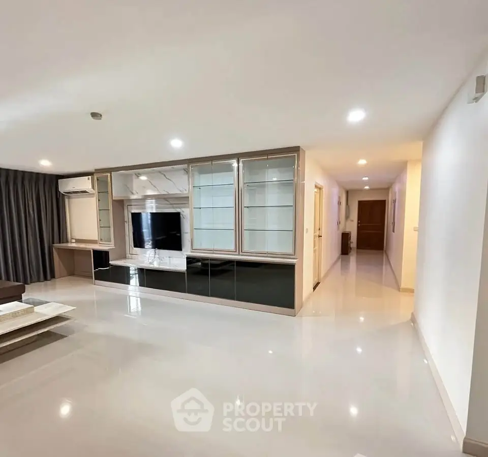 Spacious modern living room with sleek built-in entertainment center and glossy flooring.