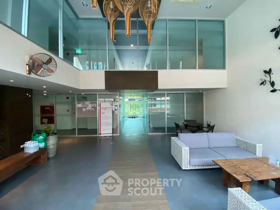 Modern lobby with stylish seating and glass partitions in a contemporary building.