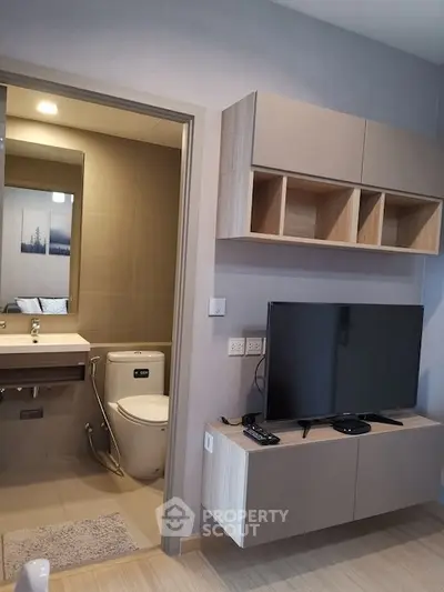 Modern living room with wall-mounted TV and view into a sleek bathroom.