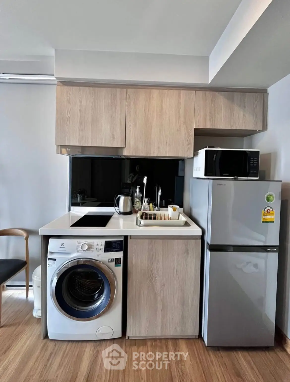 Modern kitchen with washing machine, fridge, and microwave in compact layout.