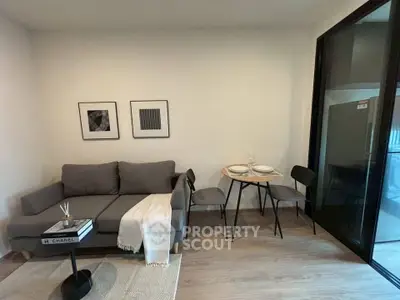 Modern living room with stylish gray sofa and dining area in open layout apartment.