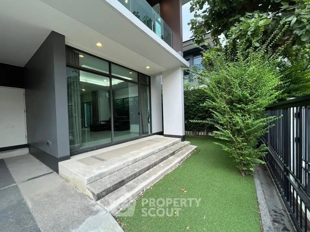 Modern building entrance with glass doors and lush greenery