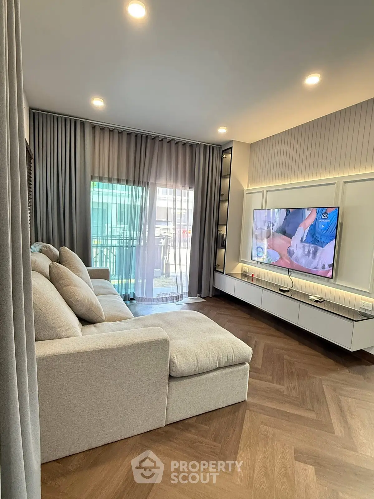 Modern living room with elegant decor and large sofa, featuring a stylish entertainment unit and floor-to-ceiling curtains.