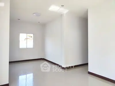 Spacious empty room with bright natural light and glossy tiled flooring.