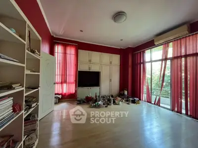 Spacious living room with red accents and large windows overlooking greenery