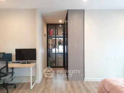 Modern bedroom with walk-in closet and workspace, featuring sleek design and ample natural light.