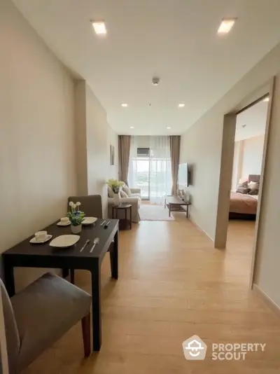 Modern apartment interior with open living and dining area, featuring wooden flooring and natural light.