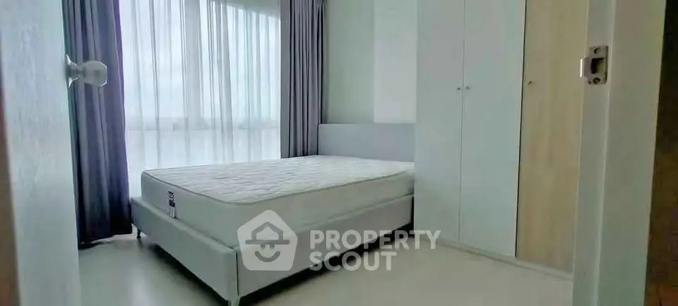 Modern bedroom with large window and built-in wardrobe in a stylish apartment.
