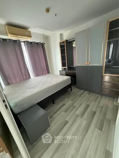 Modern bedroom with stylish flooring and ample storage in a well-lit apartment.