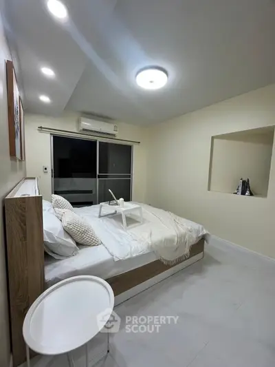 Modern bedroom with cozy lighting and minimalist decor, featuring a comfortable bed and sleek design.