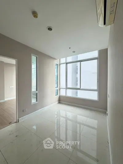 Spacious empty room with large windows and modern flooring in a high-rise apartment.