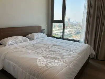 Spacious bedroom with large window offering stunning city views, perfect for urban living.