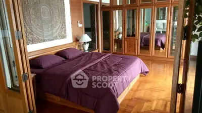 Luxurious bedroom with wooden flooring and mirrored wardrobes, featuring elegant decor and a cozy ambiance.