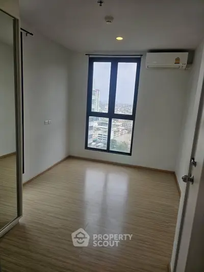 Bright empty room with large window and city view, perfect for a cozy bedroom or home office.