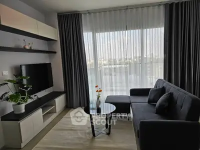 Modern living room with sleek furniture and large window offering natural light.
