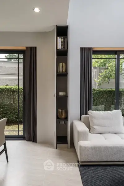 Modern living room with sleek design, large windows, and stylish furniture overlooking a lush garden.