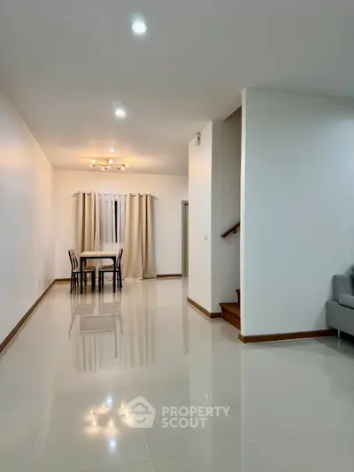 Spacious modern living room with dining area and elegant staircase in a minimalist home.