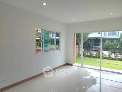 Spacious empty room with large windows overlooking a garden, ideal for customization.
