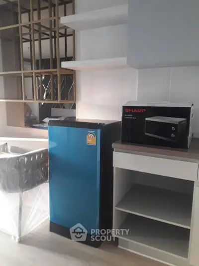 Modern kitchen with compact fridge and microwave in stylish apartment.