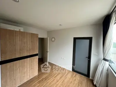 Modern bedroom with wooden flooring and large window for natural light