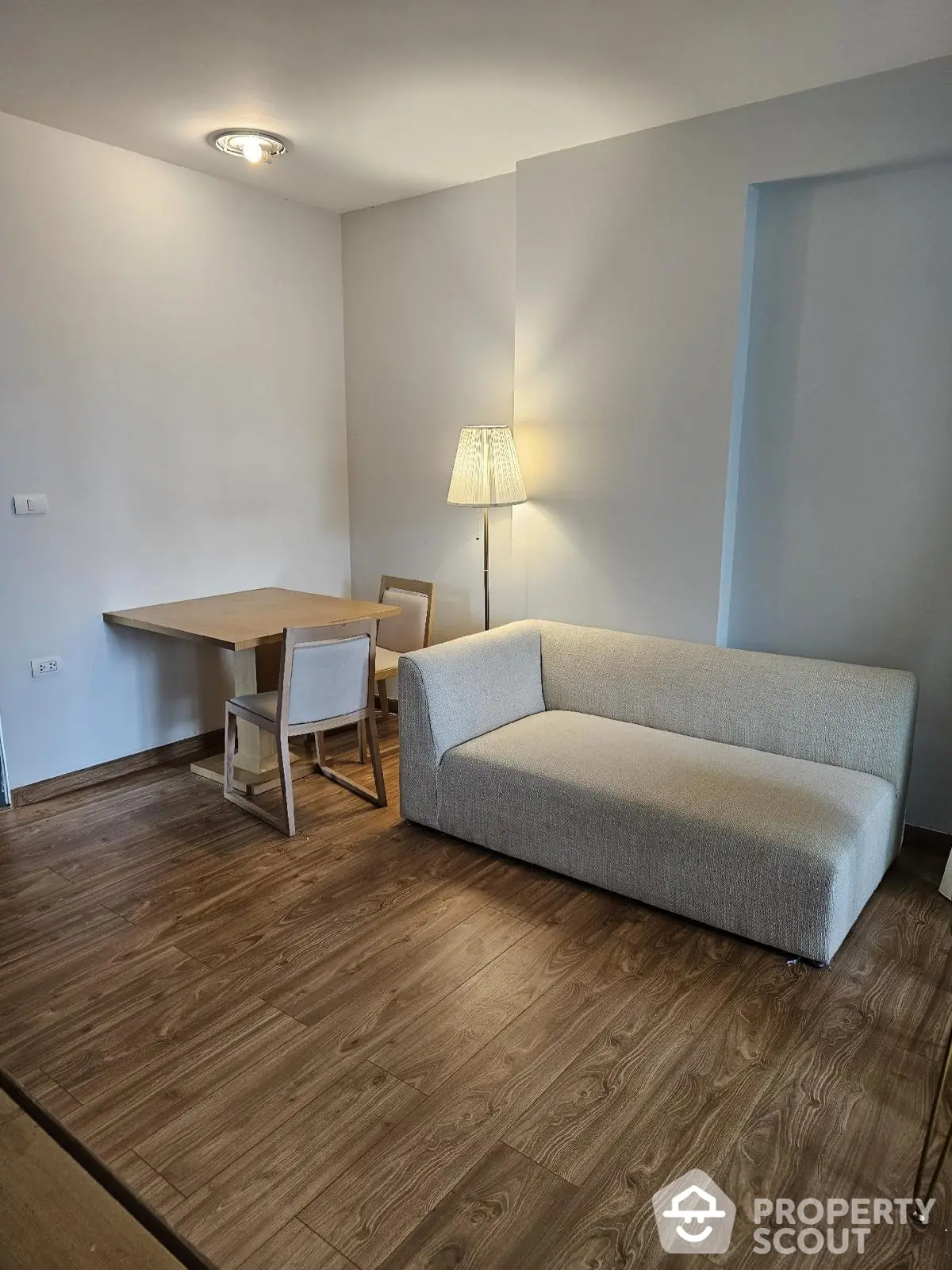 Modern living room with cozy sofa and dining area, featuring elegant wooden flooring.