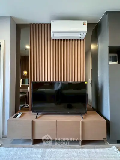 Modern living room with sleek TV setup and stylish wood paneling, featuring air conditioning for comfort.