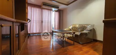 Spacious living room with wooden flooring and large window, featuring a cozy sofa and elegant decor.