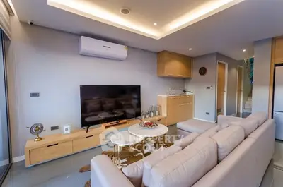 Modern living room with stylish furniture and ambient lighting, featuring a sleek TV setup and elegant decor.