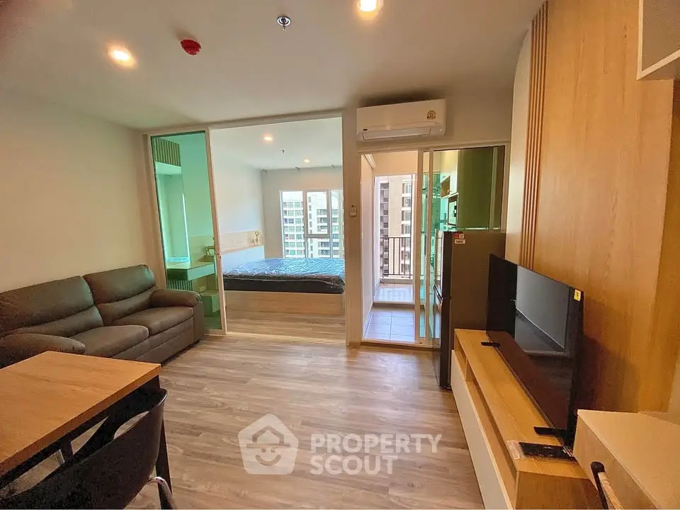 Modern apartment with open living room and bedroom, featuring sleek furniture and city view.