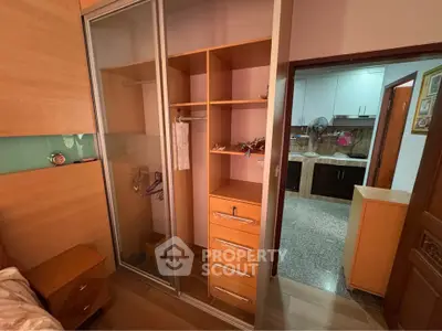 Spacious bedroom with built-in wardrobe and view into modern kitchen