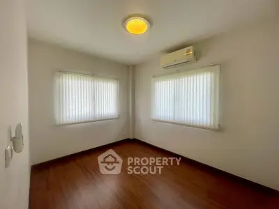 Spacious bedroom with wooden flooring and air conditioning, perfect for comfort and relaxation.