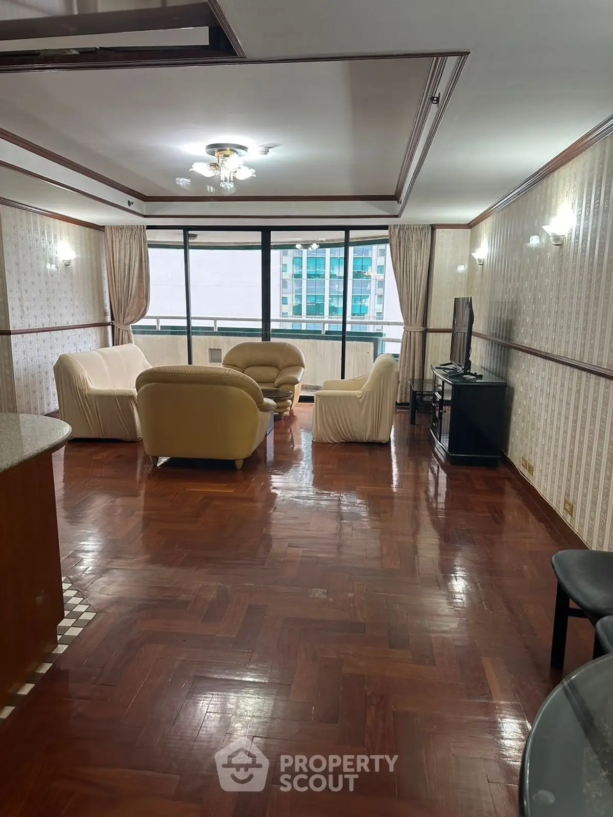 Spacious living room with elegant parquet flooring and large windows offering city views.
