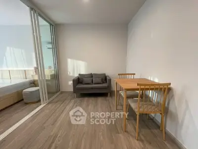 Modern studio apartment with wooden flooring, cozy sofa, and dining area.