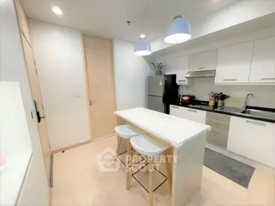 Modern kitchen with island, sleek cabinets, and stainless steel appliances in a bright apartment.