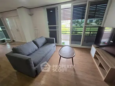 Modern living room with gray sofa, sleek coffee table, and large windows offering a scenic view.
