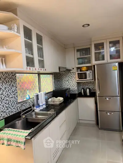 Modern kitchen with sleek cabinetry, stainless steel appliances, and mosaic backsplash.