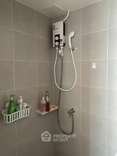 Modern bathroom with shower and water heater in tiled interior.