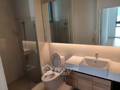 Modern bathroom with sleek fixtures and glass shower enclosure in a contemporary apartment.