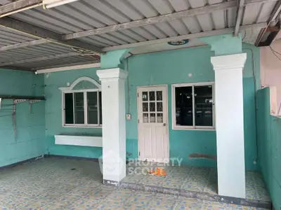 Charming turquoise exterior with covered patio and decorative columns.