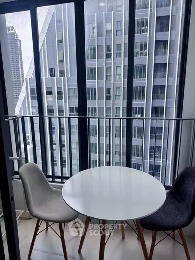 Modern balcony with city view, featuring sleek chairs and a round table, perfect for urban living.