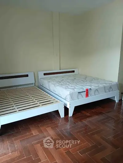 Spacious bedroom with two modern beds on elegant wooden flooring.