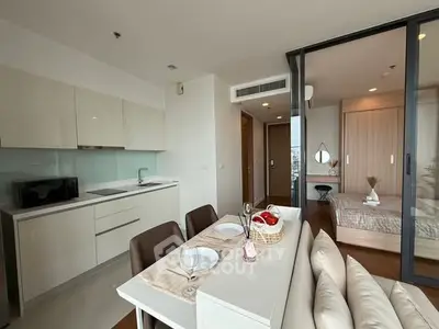 Modern open-plan kitchen and dining area with sleek design and cozy bedroom view.