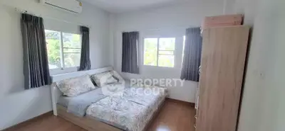 Cozy bedroom with large windows and wooden flooring, perfect for relaxation.
