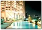 Luxurious high-rise building with illuminated poolside view at night.