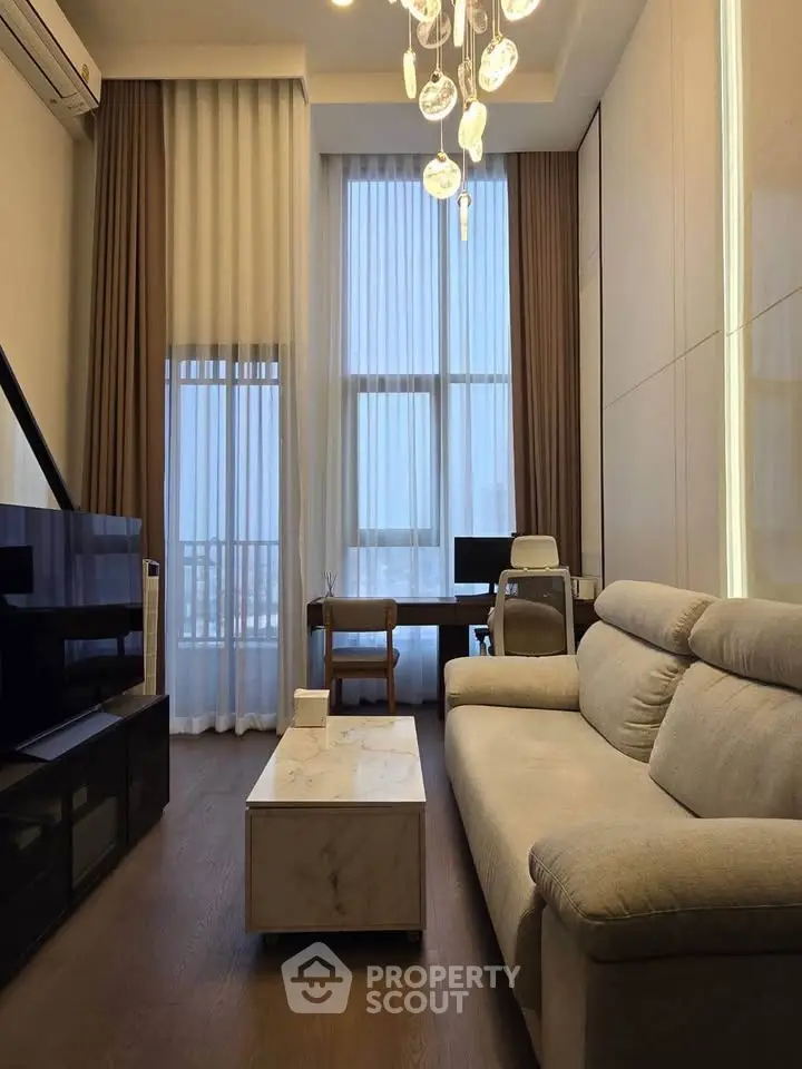 Modern living room with high ceilings, elegant chandelier, and cozy sofa, perfect for urban living.
