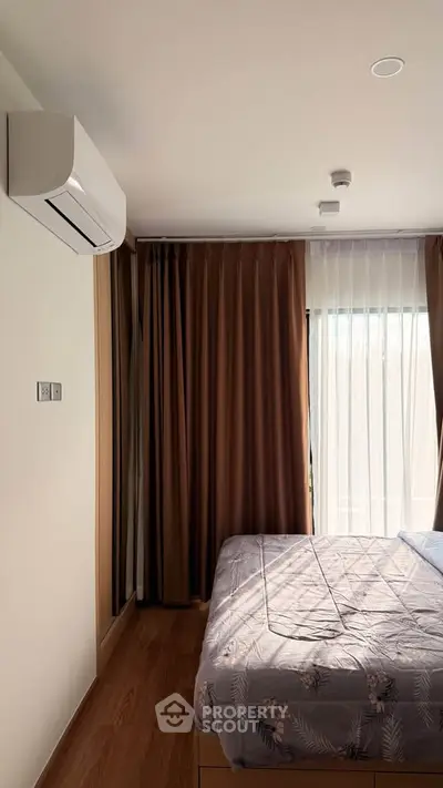 Cozy bedroom with air conditioning and natural light through large window.