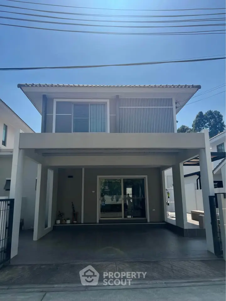 Modern two-story house with sleek design and spacious driveway under clear blue sky.